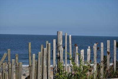 Panoramic shot of sand fence in sea against clear sky
