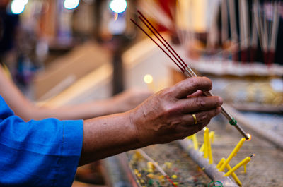 Cropped hand of man lighting incense at temple