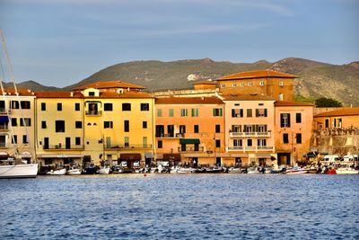 Buildings by sea against sky