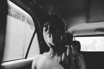 Close-up of shirtless young man smoking while sitting in car