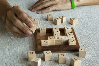 Cropped hand of person playing with toy blocks tic tac toe ox game on table