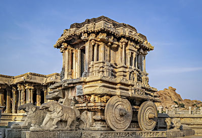 Richly sculpted stone chariot with clear blue sky background at hampi, karnataka. 