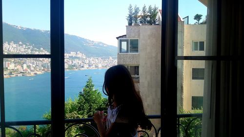 Woman looking at cityscape seen through window