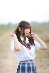 Portrait of young woman standing against sky