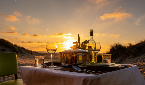 Drinks on table against sky during sunset