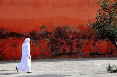 Man in traditional clothing walking on street by wall