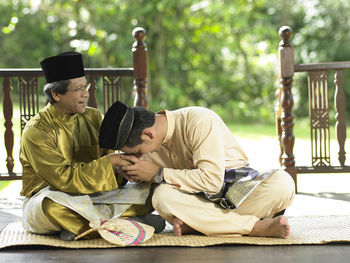 Father and son holding hands while sitting in gazebo at yard