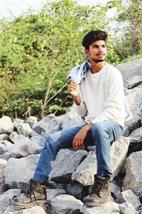 Portrait of young man sitting on rock