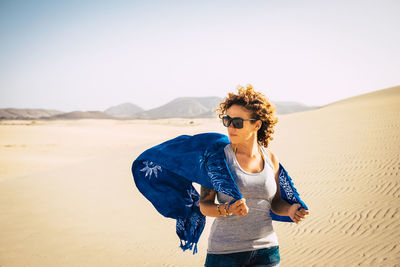 Young man standing in desert against clear sky