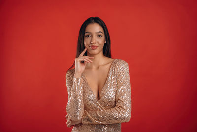 Portrait of young woman standing against yellow background