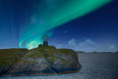 Rear view of man standing on mountain against sky at night