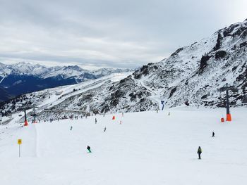 People skiing on snowcapped mountain against sky