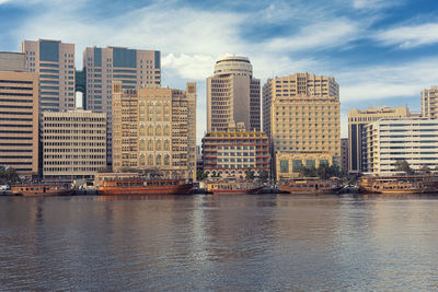 Buildings by river against sky in city