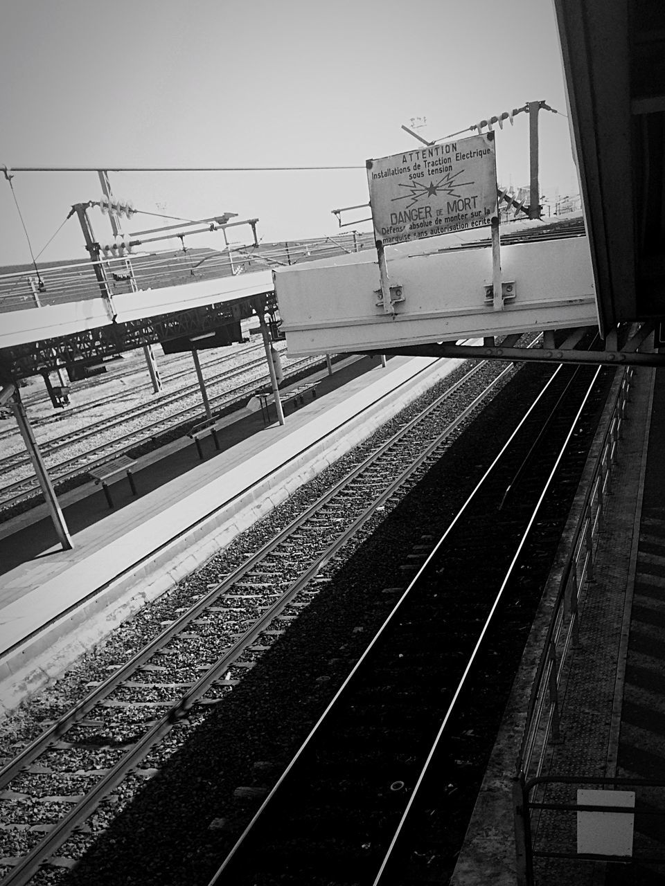 railroad track, transportation, rail transportation, public transportation, clear sky, railroad station platform, railroad station, built structure, building exterior, architecture, sky, mode of transport, electricity pylon, outdoors, day, no people, power line, fuel and power generation, train - vehicle, railway track