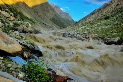 Scenic view of a muddy river captured with a long exposure and a mountain in the background