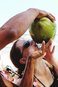 Cropped hand feeding coconut water to woman