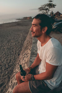 Young man using mobile phone while sitting on beach