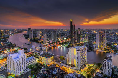 High angle view of illuminated city buildings against sky during sunset