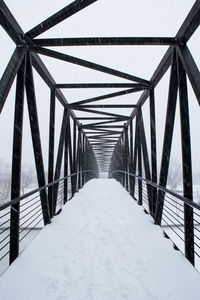 Metallic bridge against sky during snowfall