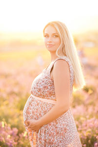 Smiling pregnant woman standing on field