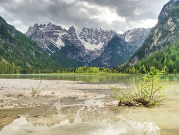 Lovely nature scenery with rocky peaks above coniferous forest and beautiful lake. smooth water