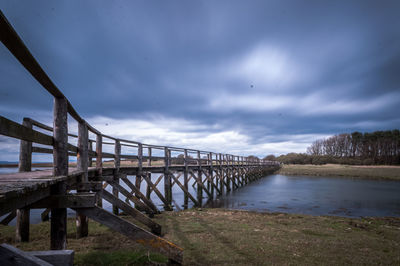 Bridge over river against cloudy sky