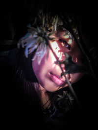 Close-up portrait of woman by flowers at night