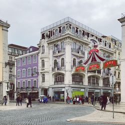 People walking on town square against sky in city