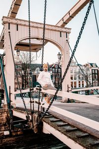 Man sitting on bridge in city