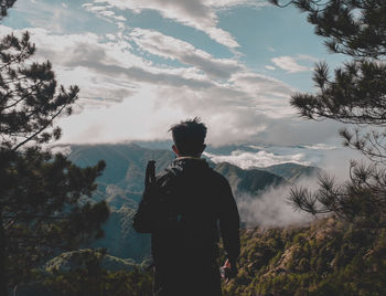 Rear view of man looking at mountain against sky