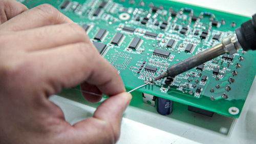 Cropped hand of worker examining mother board