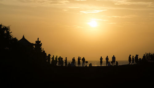 Silhouette people on beach against sky during sunset