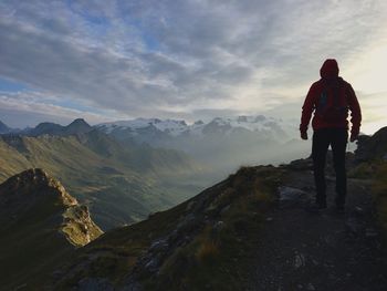 Rear view of man standing on mountain against sky