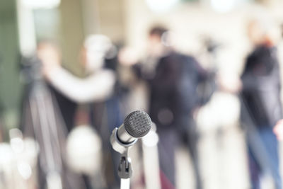 Close-up of microphone with people standing in background
