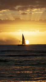 Silhouette sailboat in sea against sky during sunset