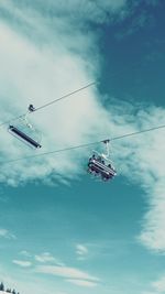 Low angle view of overhead cable cars against cloudy sky