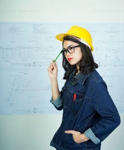 Young woman holding yellow while standing against the wall