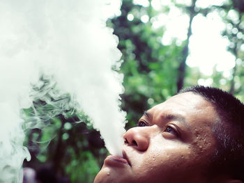 Close-up of man smoking against trees