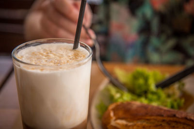 Close-up of hand holding drink on table