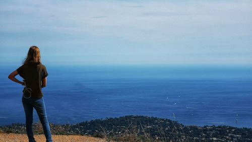 Rear view of woman looking at sea while standing on cliff 