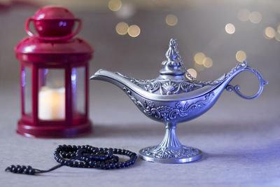 Close-up of magic lamp with bead necklace and lantern on table