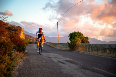 Man riding bicycle on road against sky