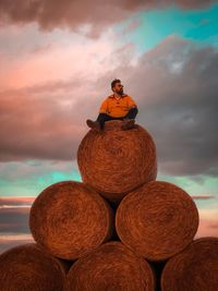 Rear view of man standing by stack against sea during sunset