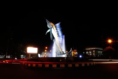 Light trails on street against sky in city at night