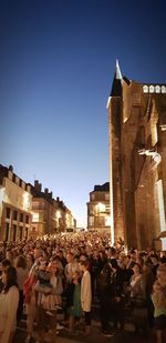 Group of people in illuminated building against sky in city