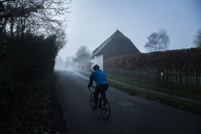 Rear view of man riding bicycle on road
