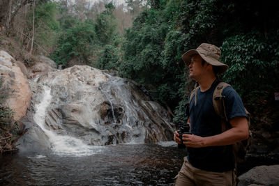 Man standing on rock looking at waterfall in forest