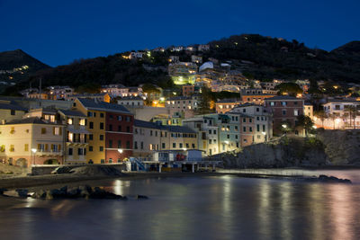 Townscape by sea against sky at night