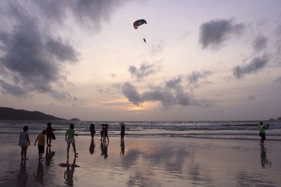 People standing on beach against sky during sunset