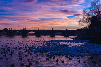 Bridge over river against sky at sunset